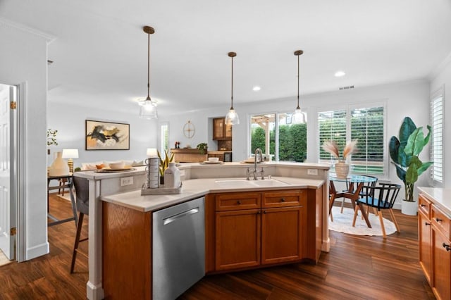 kitchen with dark wood-type flooring, sink, hanging light fixtures, stainless steel dishwasher, and an island with sink