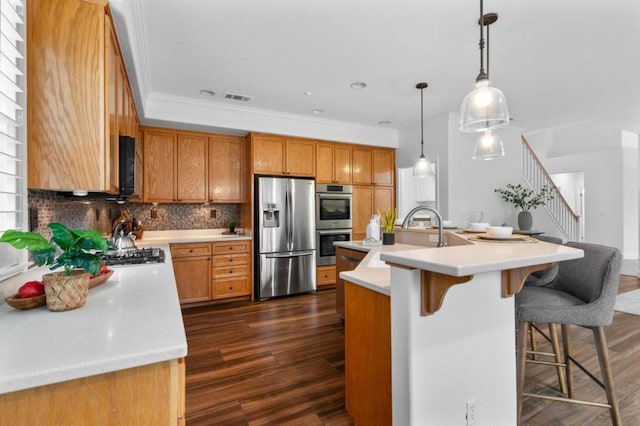 kitchen with a kitchen bar, sink, hanging light fixtures, an island with sink, and stainless steel appliances