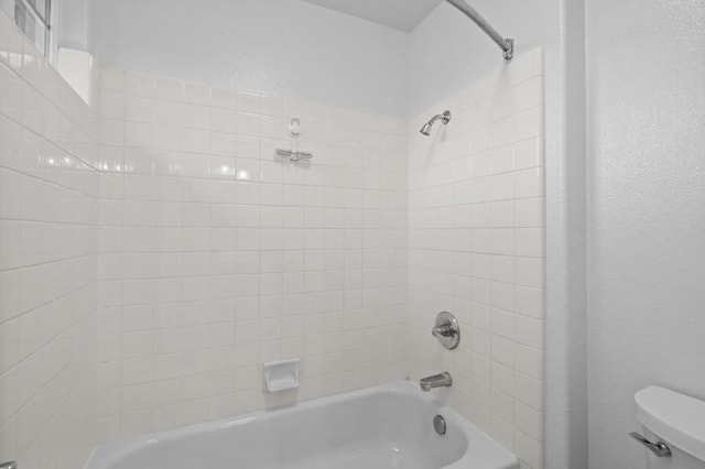 bathroom with toilet and tiled shower / bath combo