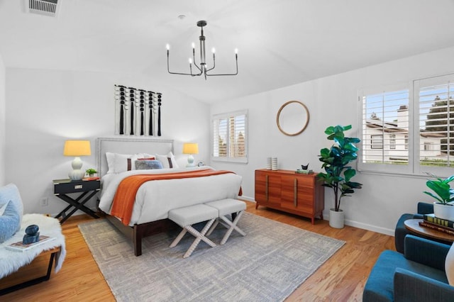 bedroom featuring lofted ceiling, a notable chandelier, and light hardwood / wood-style floors