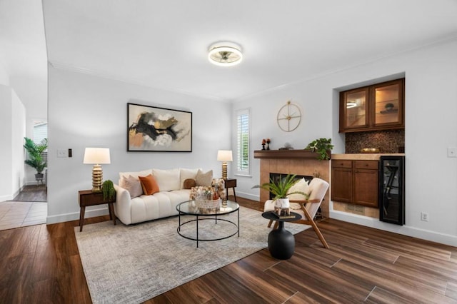 living room with ornamental molding, dark wood-type flooring, bar area, and beverage cooler