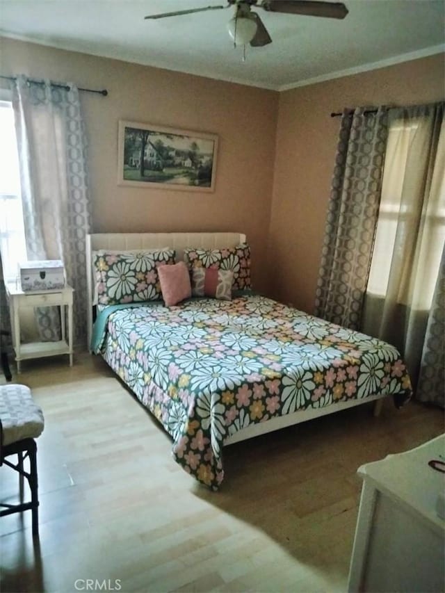 bedroom featuring a ceiling fan, ornamental molding, and wood finished floors