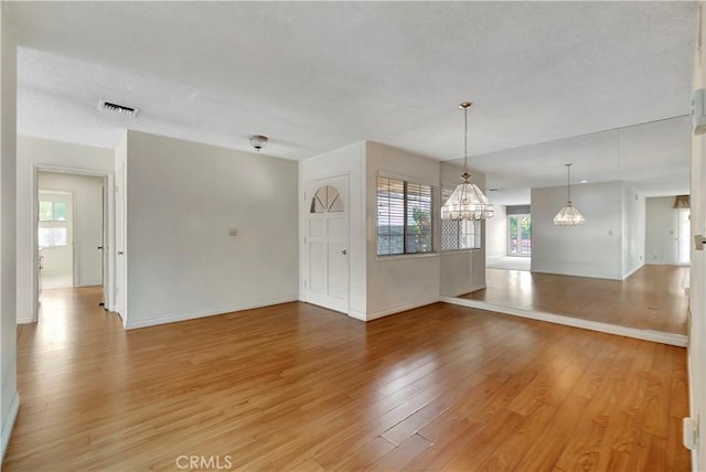 empty room featuring hardwood / wood-style flooring and an inviting chandelier