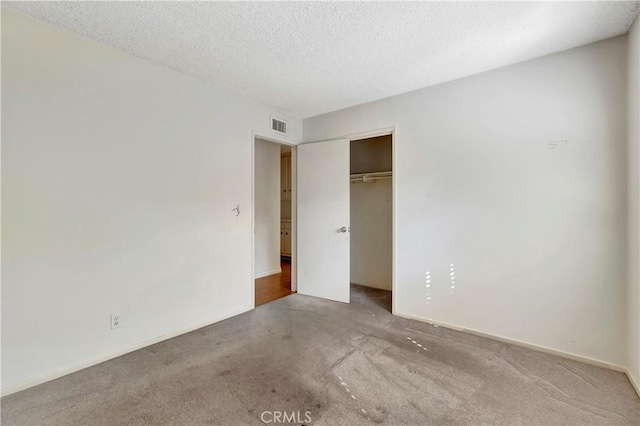 unfurnished bedroom featuring light carpet, a closet, and a textured ceiling