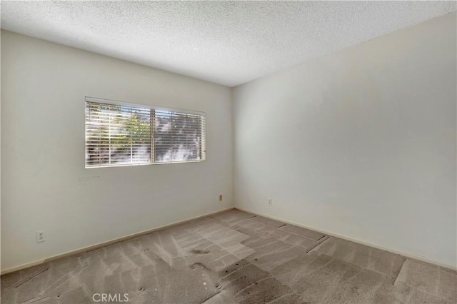 spare room featuring light colored carpet and a textured ceiling