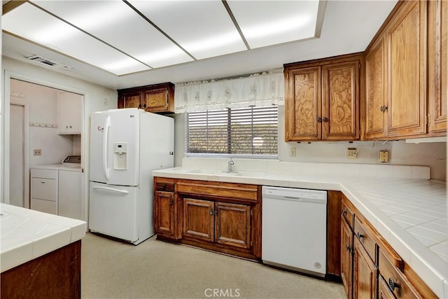 kitchen featuring sink, white appliances, tile counters, and washing machine and dryer