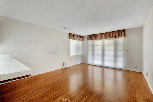 spare room featuring hardwood / wood-style floors and a textured ceiling