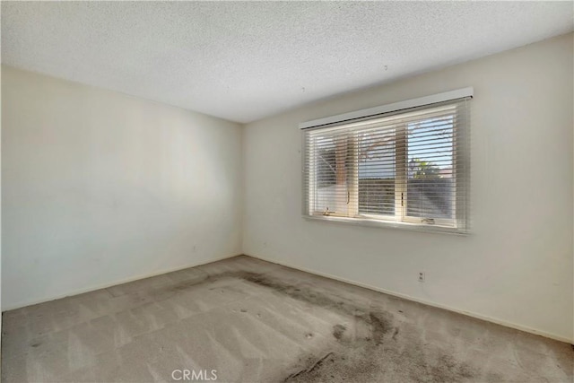 unfurnished room featuring light colored carpet and a textured ceiling