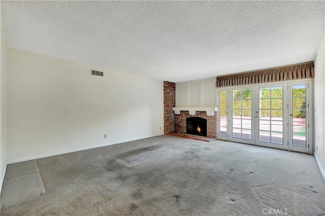 unfurnished living room with french doors, a brick fireplace, carpet, and a textured ceiling