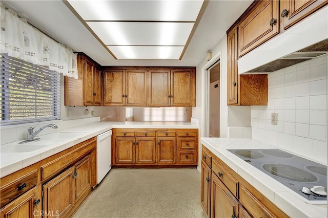 kitchen with sink, tasteful backsplash, tile counters, dishwasher, and electric stovetop