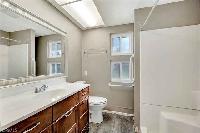 bathroom featuring hardwood / wood-style flooring, a shower, vanity, and toilet