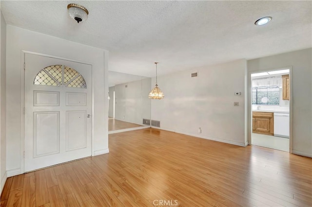 foyer with a textured ceiling, light hardwood / wood-style flooring, and a notable chandelier