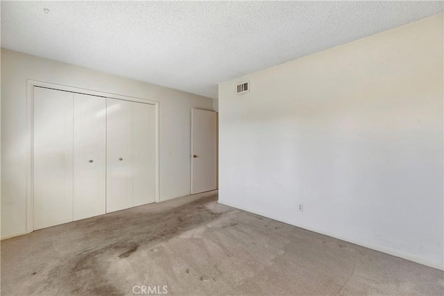 unfurnished bedroom featuring a closet, light carpet, and a textured ceiling