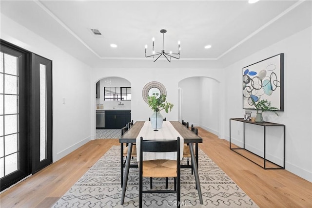 dining space featuring a tray ceiling, a chandelier, and light hardwood / wood-style flooring