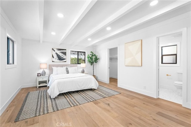 bedroom with beamed ceiling, wood-type flooring, a spacious closet, and ensuite bathroom