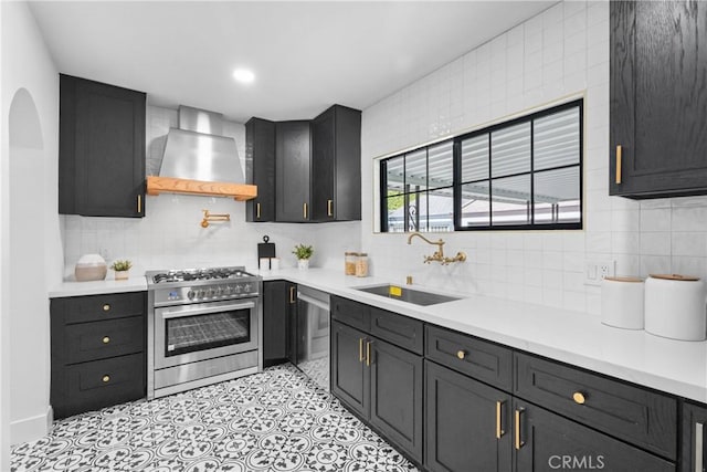 kitchen with wall chimney exhaust hood, stainless steel appliances, sink, and decorative backsplash