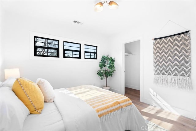 bedroom featuring a spacious closet, light hardwood / wood-style floors, and a closet