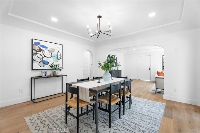 dining room featuring light hardwood / wood-style flooring, a raised ceiling, and a chandelier