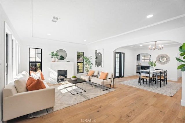 living room with a notable chandelier, a wealth of natural light, and light wood-type flooring