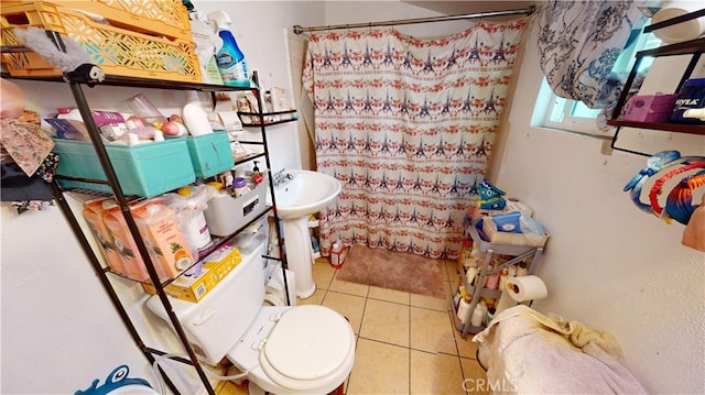 bathroom with tile patterned flooring, walk in shower, sink, and toilet