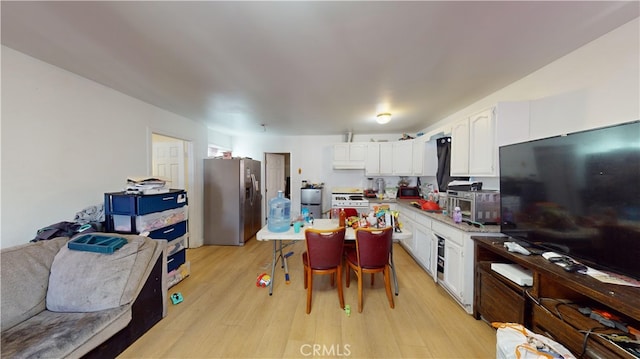 kitchen with white cabinetry, light wood-type flooring, white gas range oven, and stainless steel refrigerator with ice dispenser