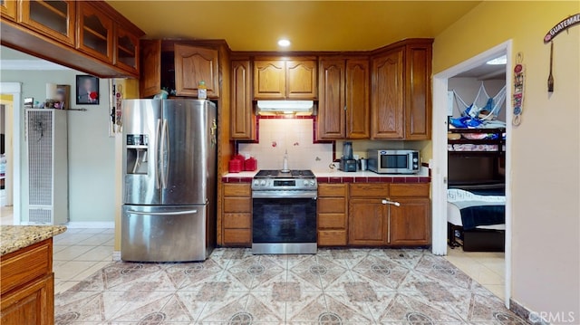 kitchen with light tile patterned flooring, stainless steel appliances, and backsplash