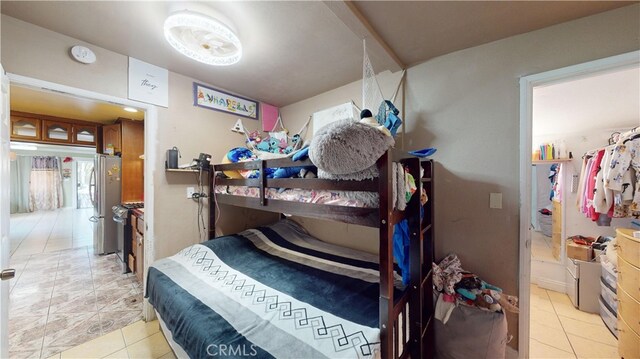 bedroom with light tile patterned floors and stainless steel refrigerator