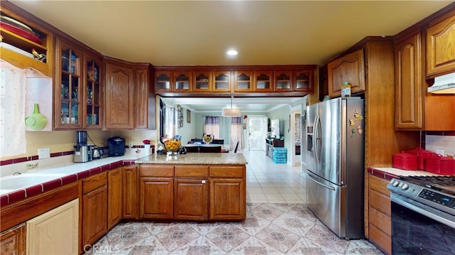 kitchen featuring hanging light fixtures, tile counters, sink, and appliances with stainless steel finishes