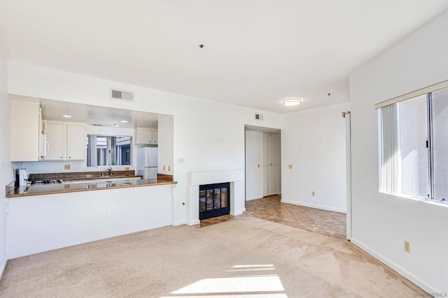 unfurnished living room with light carpet and sink