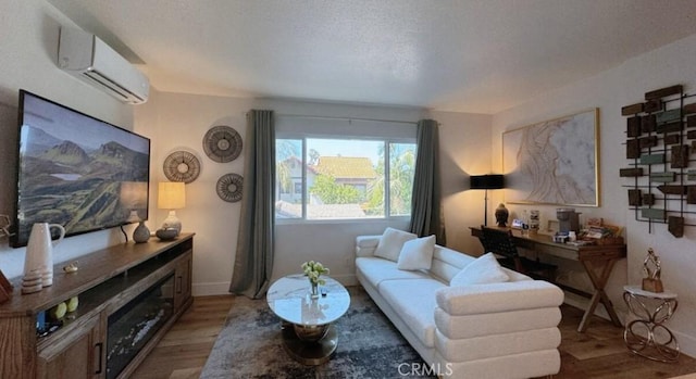 living area with hardwood / wood-style floors, an AC wall unit, and a textured ceiling