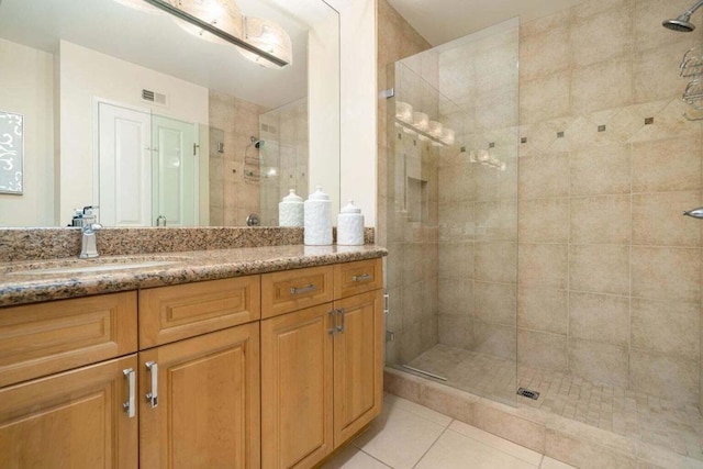 bathroom with tile patterned flooring, vanity, and a tile shower