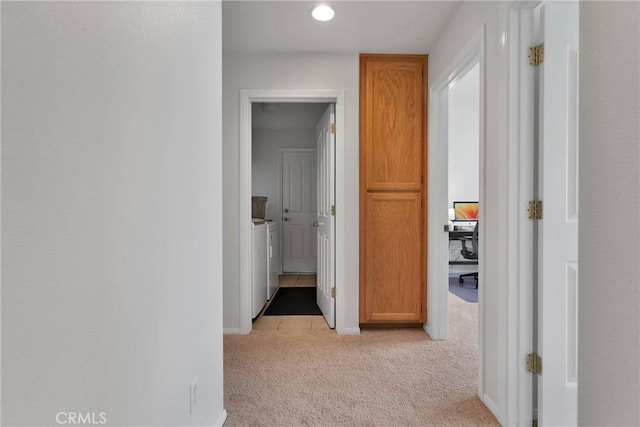 hallway with light colored carpet and washer and dryer