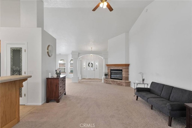 living room with ceiling fan, light colored carpet, decorative columns, and a towering ceiling