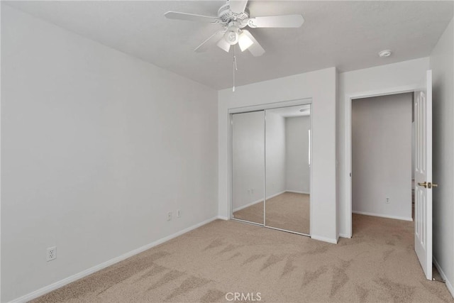 unfurnished bedroom with light carpet, ceiling fan, and a closet