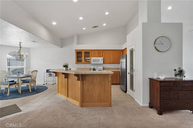 kitchen with light carpet, tile countertops, range, and stainless steel refrigerator