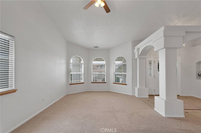 carpeted empty room featuring ceiling fan and ornate columns