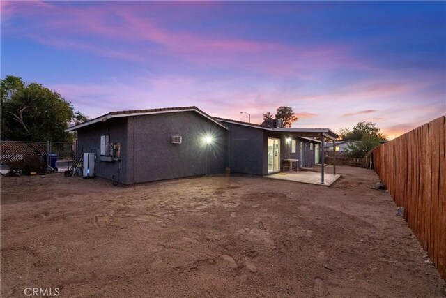 back house at dusk with a patio area