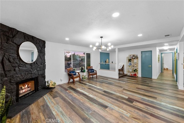 dining room featuring a notable chandelier, a stone fireplace, and dark wood-type flooring