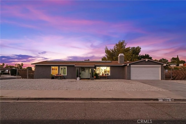 ranch-style house featuring a garage and solar panels