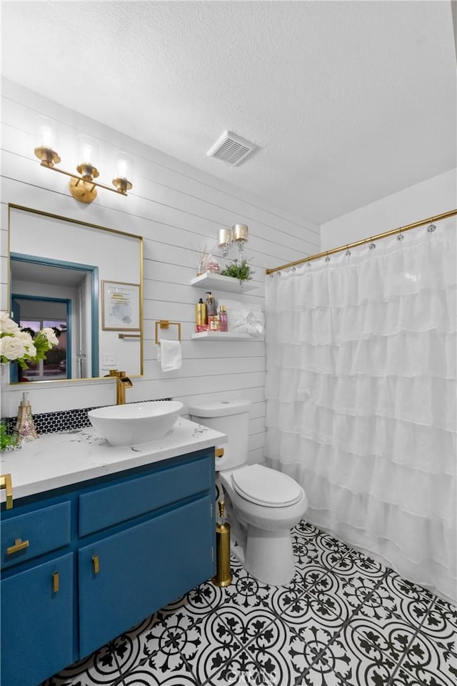 bathroom featuring tile patterned floors, toilet, a textured ceiling, vanity, and curtained shower