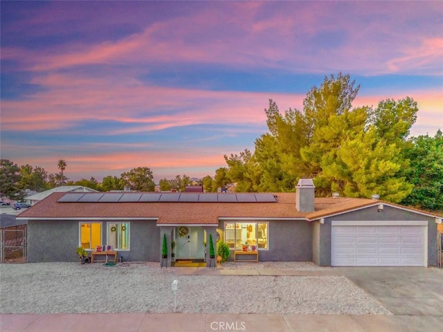 ranch-style house featuring a garage and solar panels