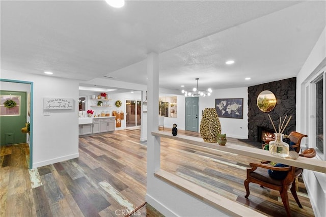 interior space with wood-type flooring, a stone fireplace, pendant lighting, and a chandelier