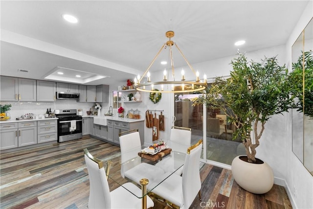 dining area featuring dark hardwood / wood-style flooring, a chandelier, and a tray ceiling