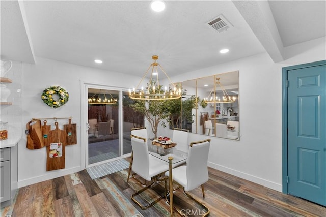 dining area with dark wood-type flooring and an inviting chandelier