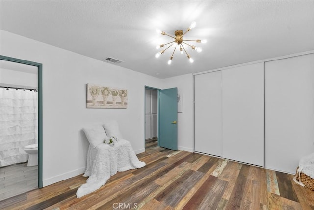 bedroom featuring connected bathroom, dark hardwood / wood-style floors, a closet, and a chandelier