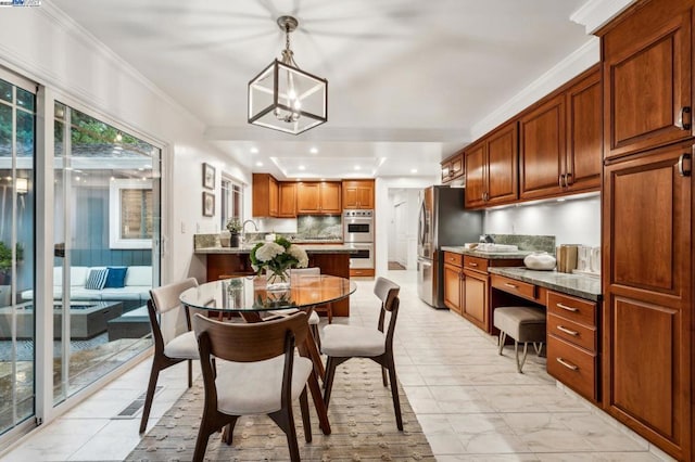 dining space featuring sink, built in desk, ornamental molding, and a chandelier