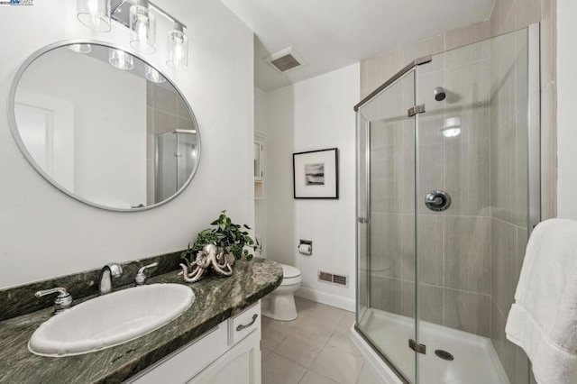 bathroom with vanity, tile patterned flooring, a shower with door, and toilet