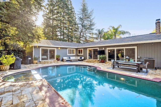 view of pool with an outdoor living space, a patio, and central air condition unit