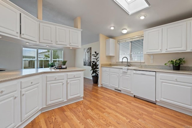 kitchen with a skylight, sink, white cabinets, light hardwood / wood-style floors, and white dishwasher