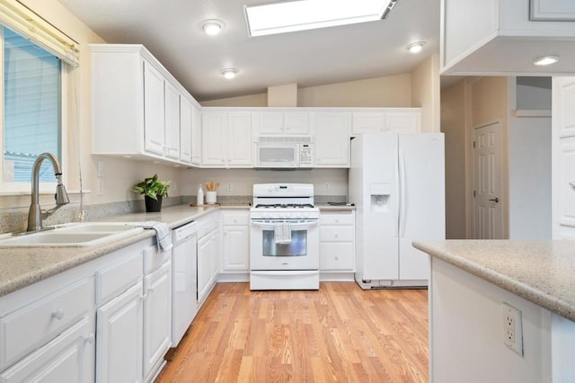 kitchen featuring sink, white appliances, lofted ceiling with skylight, and white cabinets